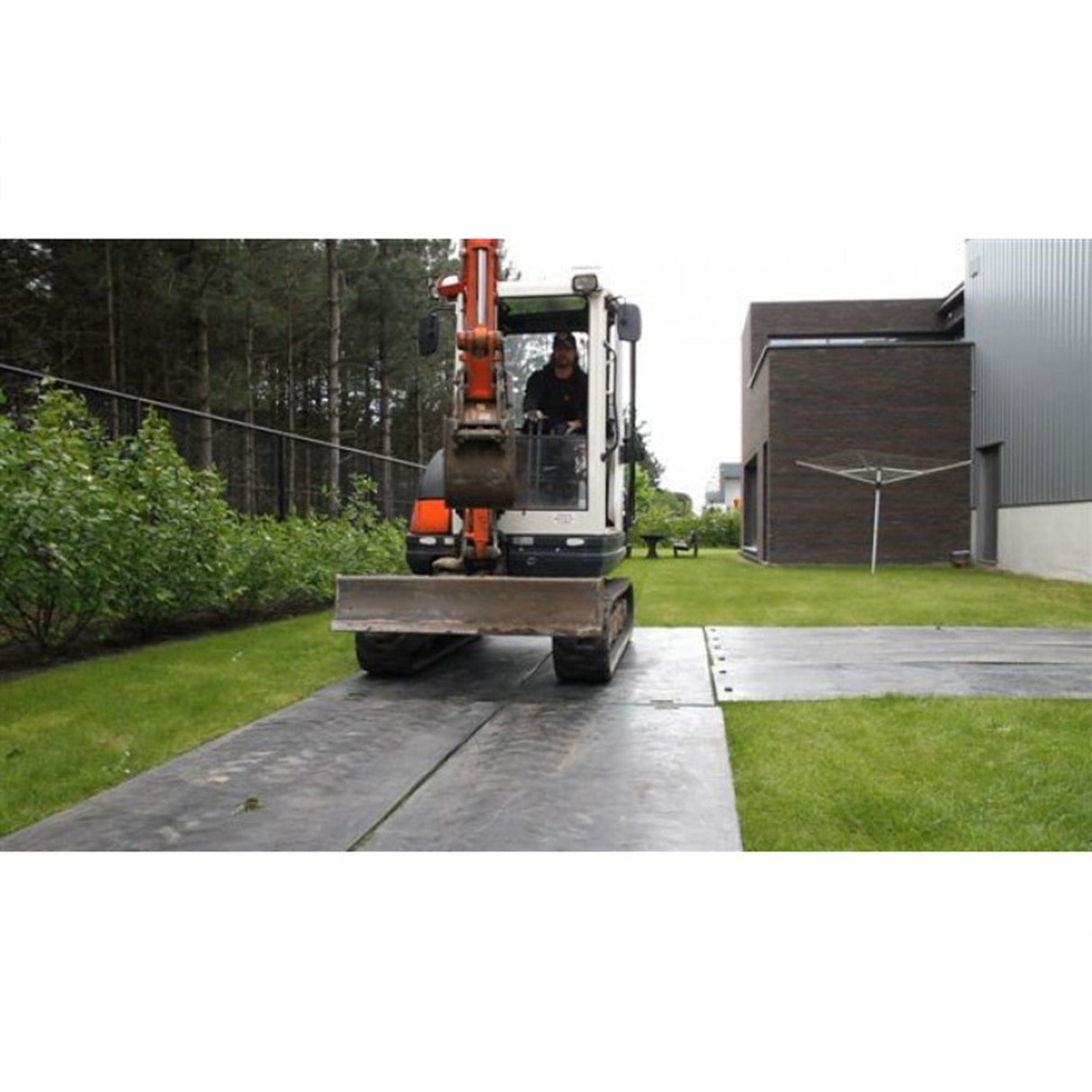 Tracked mini excavator driving along EuroTrak access mats laid across a garden site