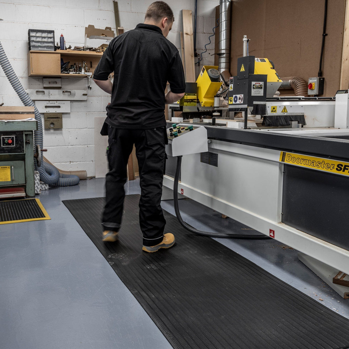 Safety boot on the edge of an Ergotred anti-fatigue mat during workshop use