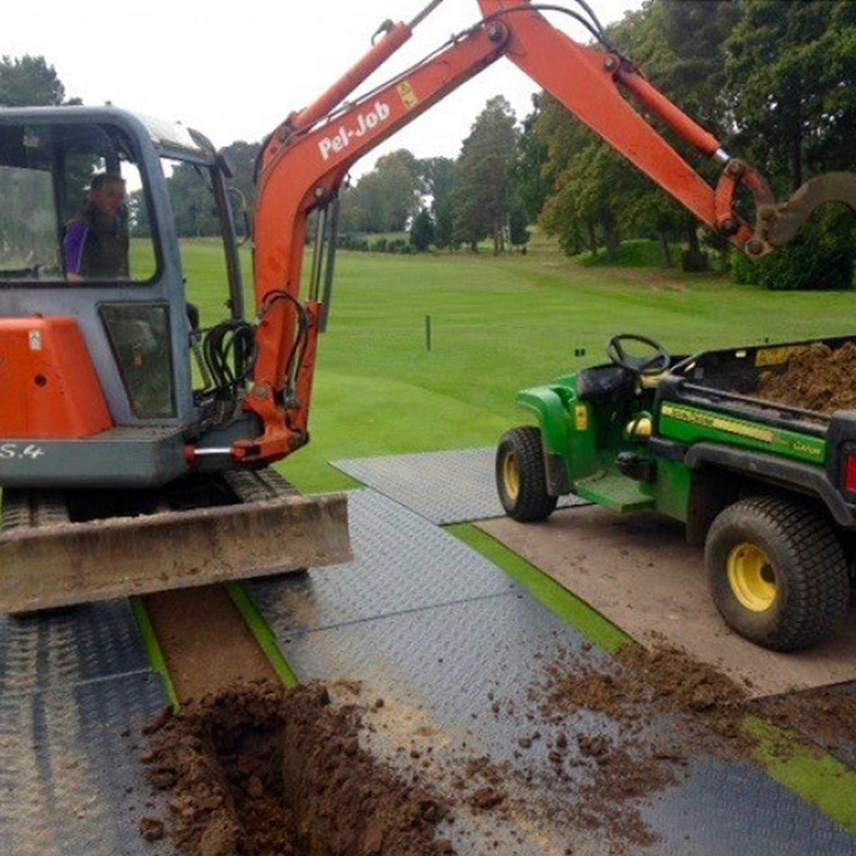 DuraMatt access mats laid on a golf course fairway with an excavator and utility vehicle positioned on top