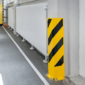 Right-angle protector bolted at a wall corner in an indoor corridor, guarding the edge next to pipework