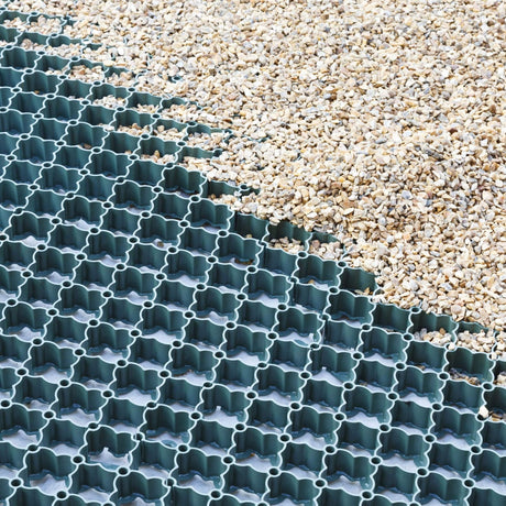 Green gravel grid partially filled with buff gravel aggregate, edge of the grid shown next to loose stone