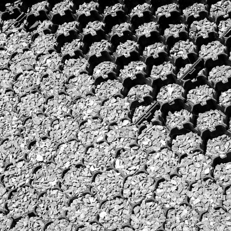 Close-up aerial view of black gravel grid cells fully filled with light grey stone aggregate