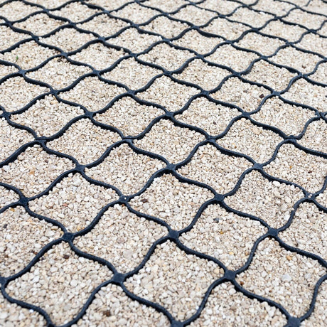 Black gravel grid filled with buff gravel aggregate, close diagonal view of a completed driveway surface